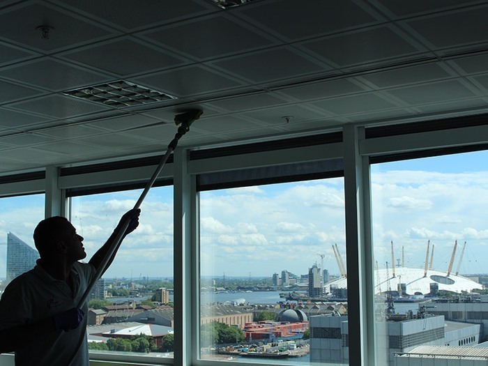 Sử dụng chổi lông làm sạch bụi trên trần nhôm trước khi vệ sinh