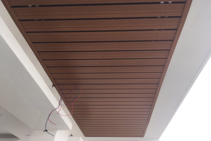 Trần nhôm giả gỗ G-shaped với màu vân gỗ nâu đậm trong thiết kế mái hiên