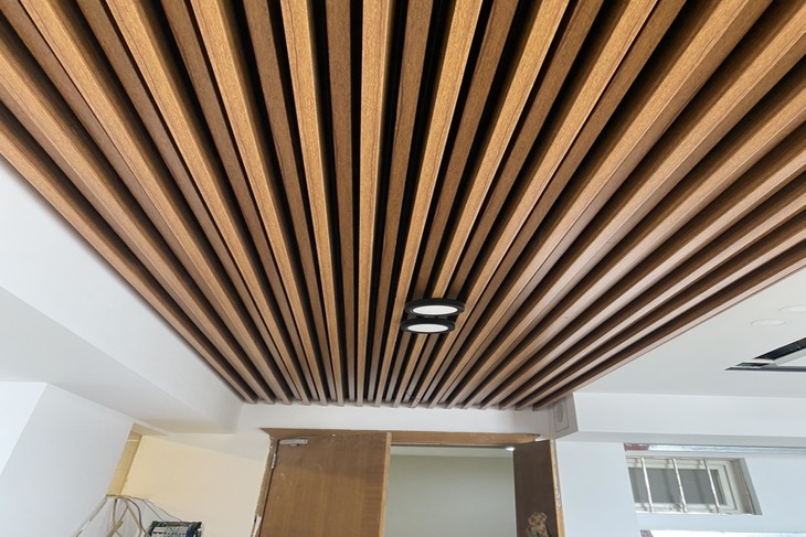 Trần nhôm giả gỗ U-shaped được lắp một phần tại phòng khách mang tới vẻ đẹp độc đáo, khác lạ